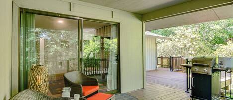 A covered outdoor area with wicker furniture, a grill, and a sliding glass door leading to a deck.