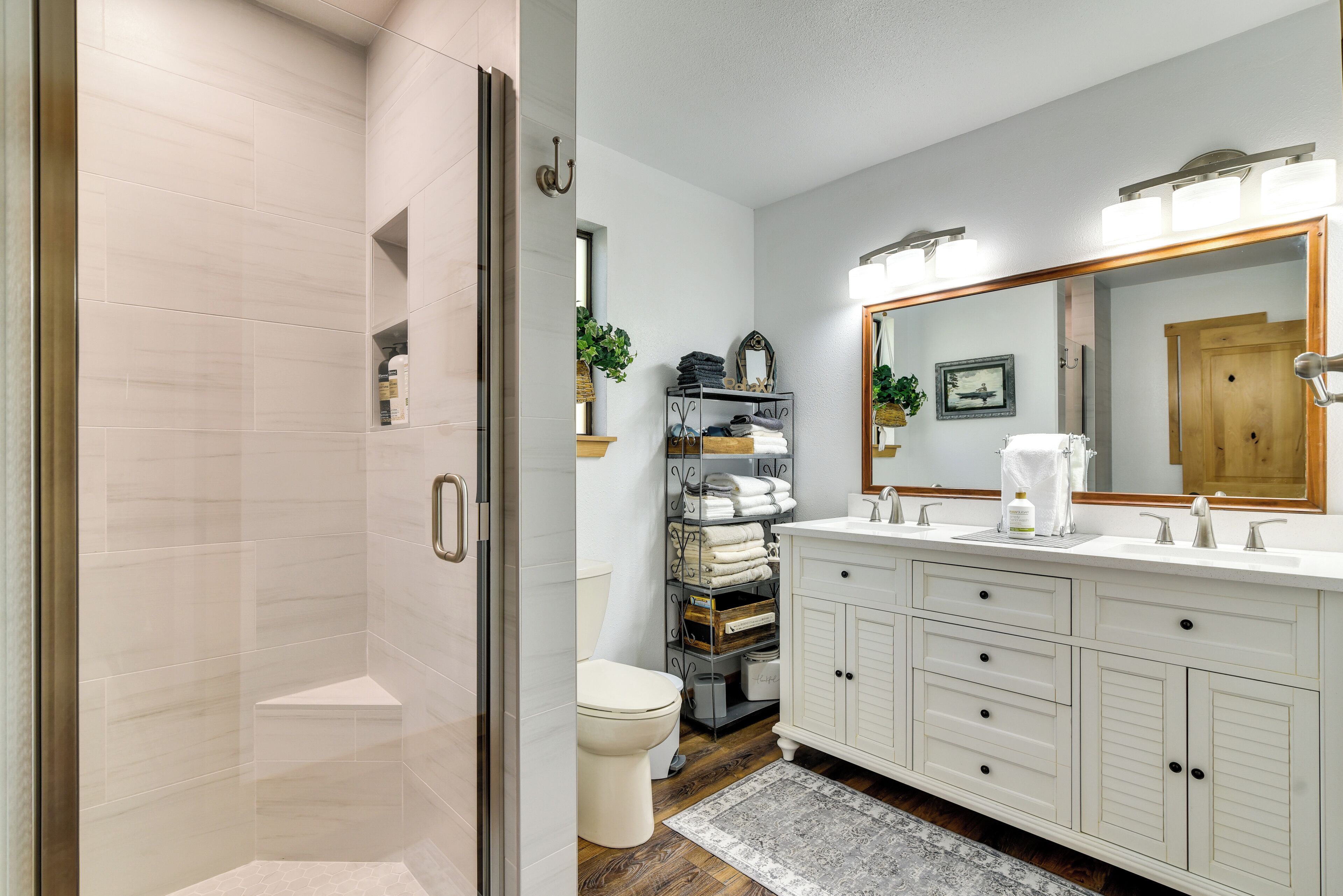 A modern bathroom with a walk-in shower, a toilet, and a vanity with a large mirror.