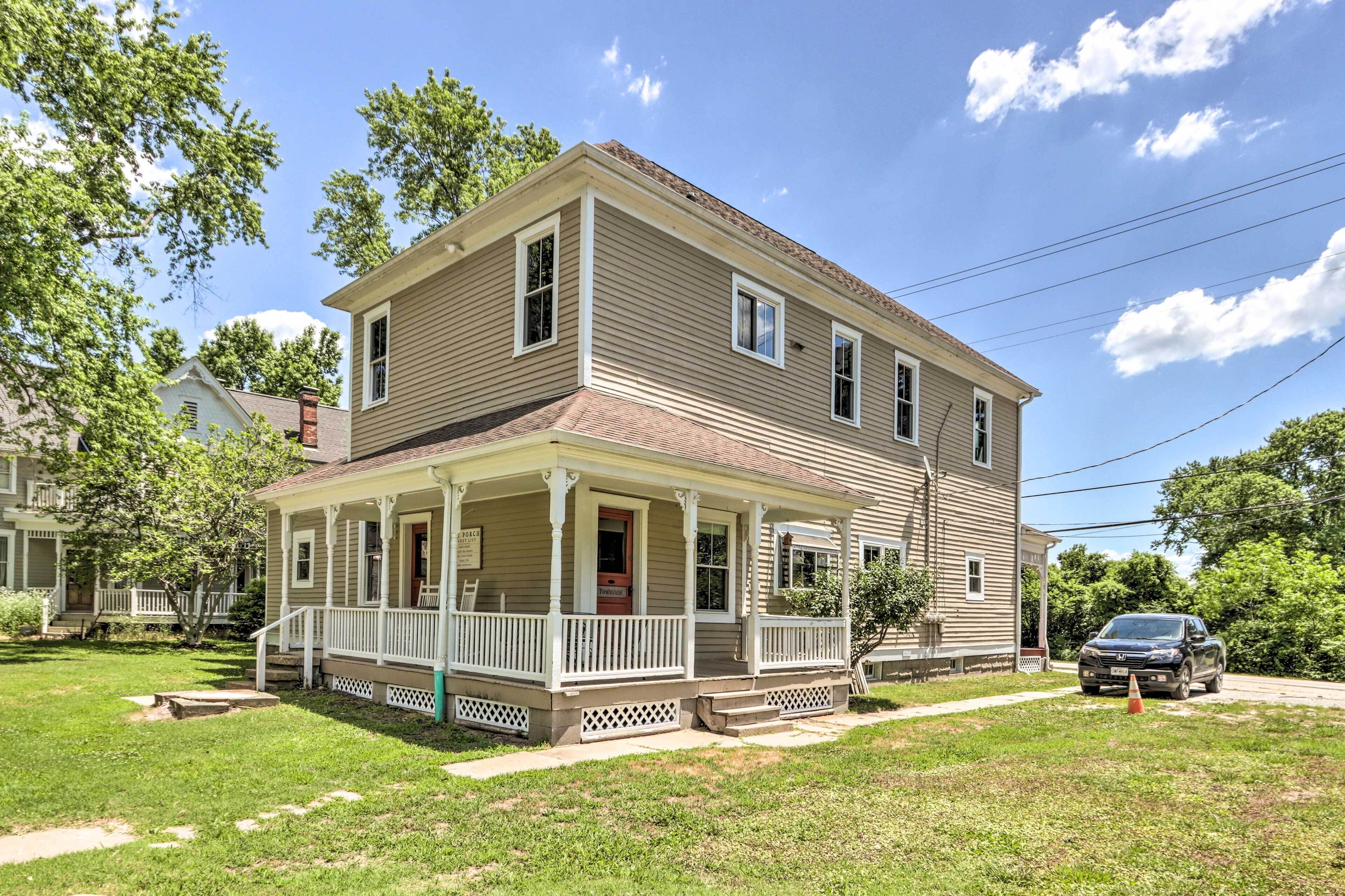 A two-story house with a porch, a driveway, and a parked car.
