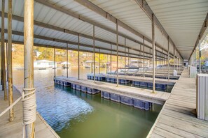 A covered dock area with multiple wooden platforms extending over water, connected by a metal roof structure. - Private Dock: Grand Lake Family Home (Eucha)