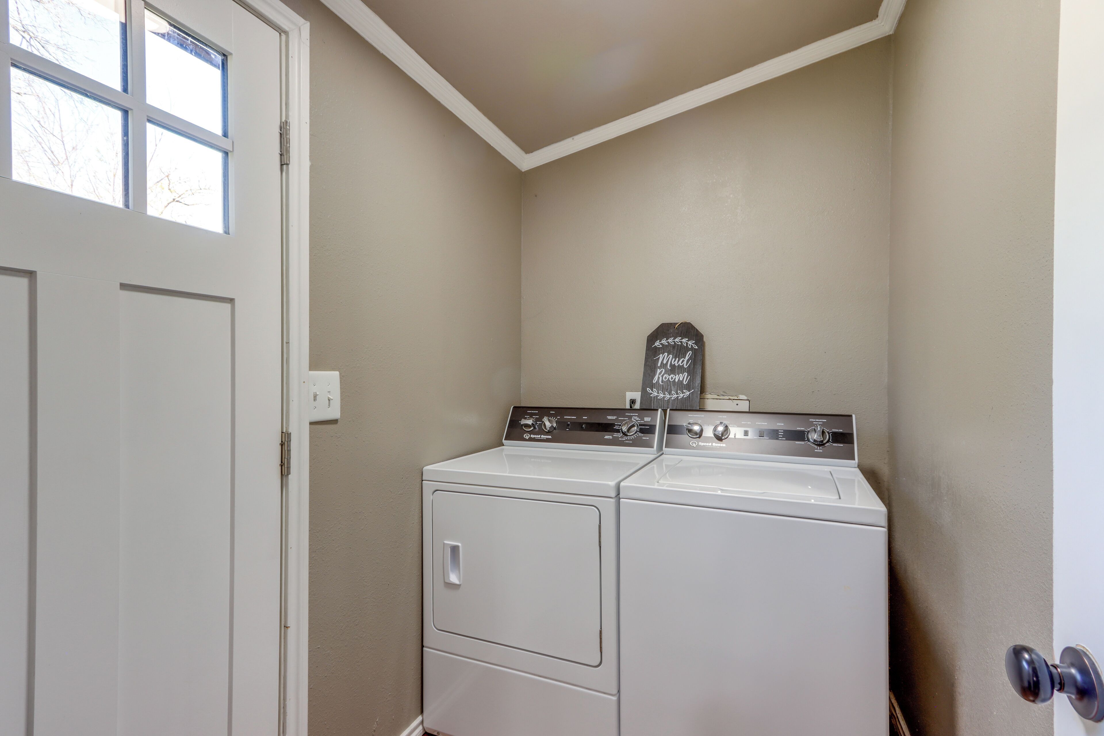 A laundry room with a washer and dryer, a chalkboard sign, and a door.