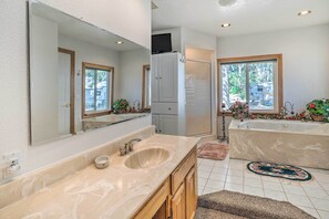 Une salle de bain avec un double lavabo, un grand miroir et une baignoire.