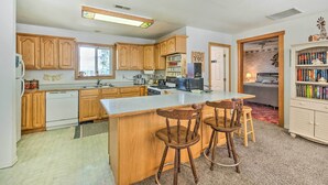 A kitchen with wooden cabinets, a central island with bar stools, a microwave, and a bookshelf. - Caldwell Country Home on Quiet Acreage (Caldwell)