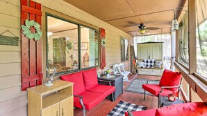 Une véranda avec un canapé rouge, un meuble en bois et un tapis à carreaux.