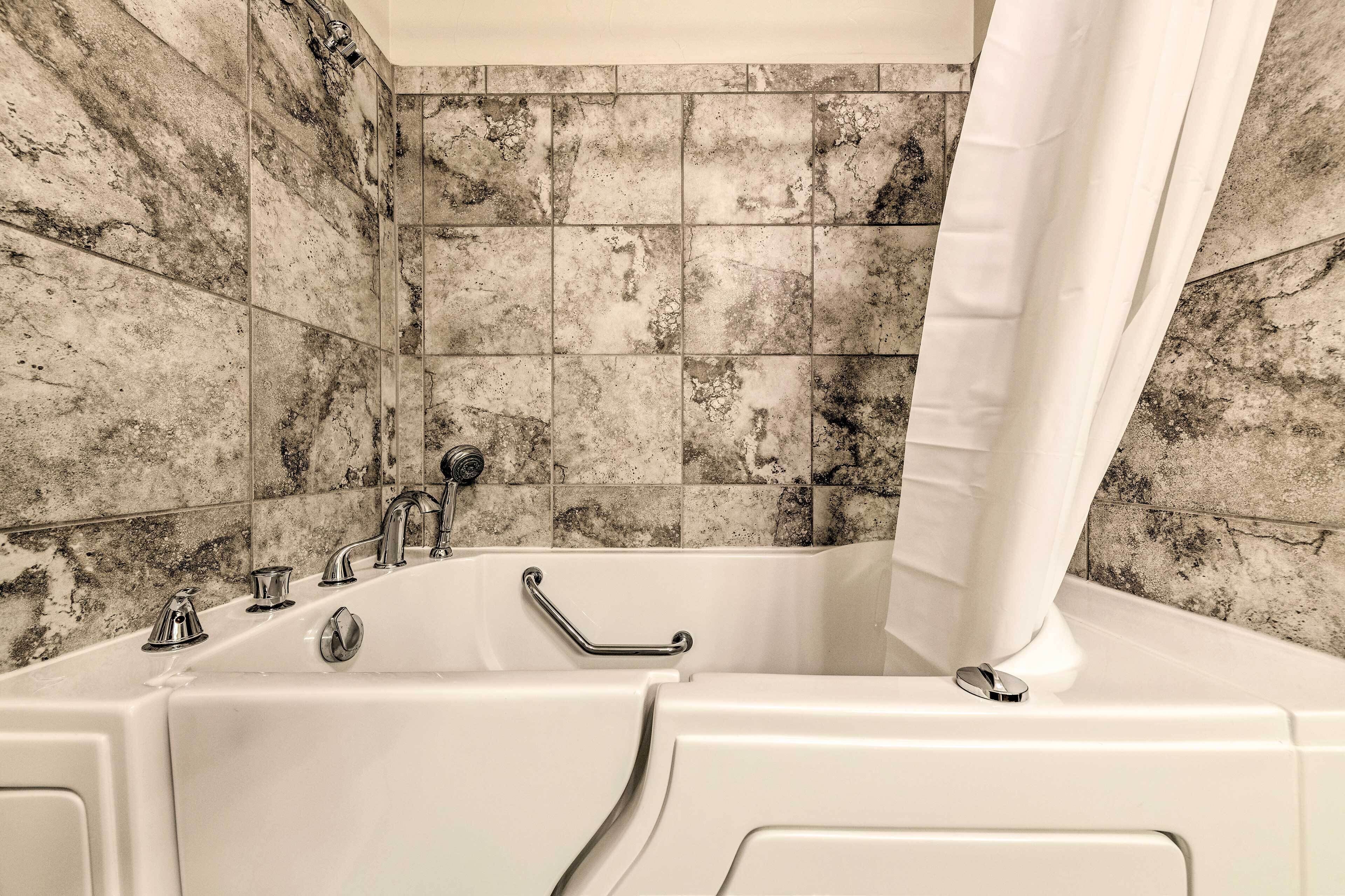 Une salle de bain équipée d’une baignoire, d’une barre d’appui et d’un rideau de douche.