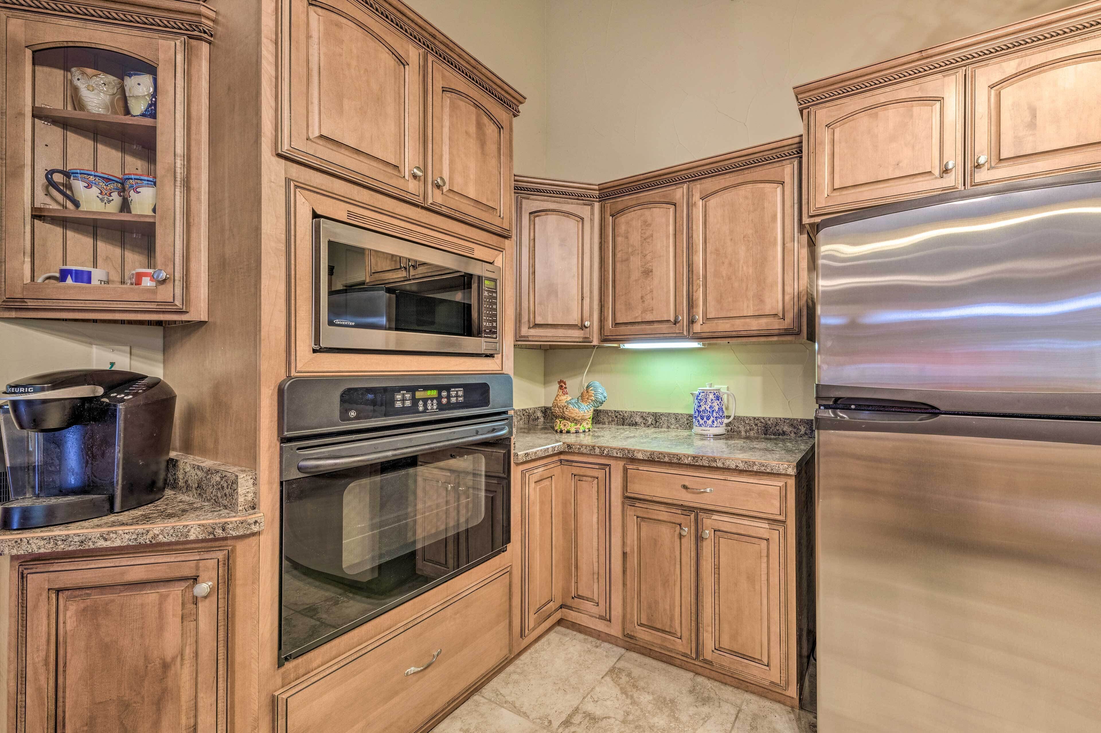 A kitchen with wooden cabinets, a stainless steel refrigerator, a microwave, an oven, and a coffee maker.