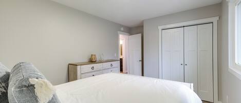 A bedroom with a bed, dresser, and closet.