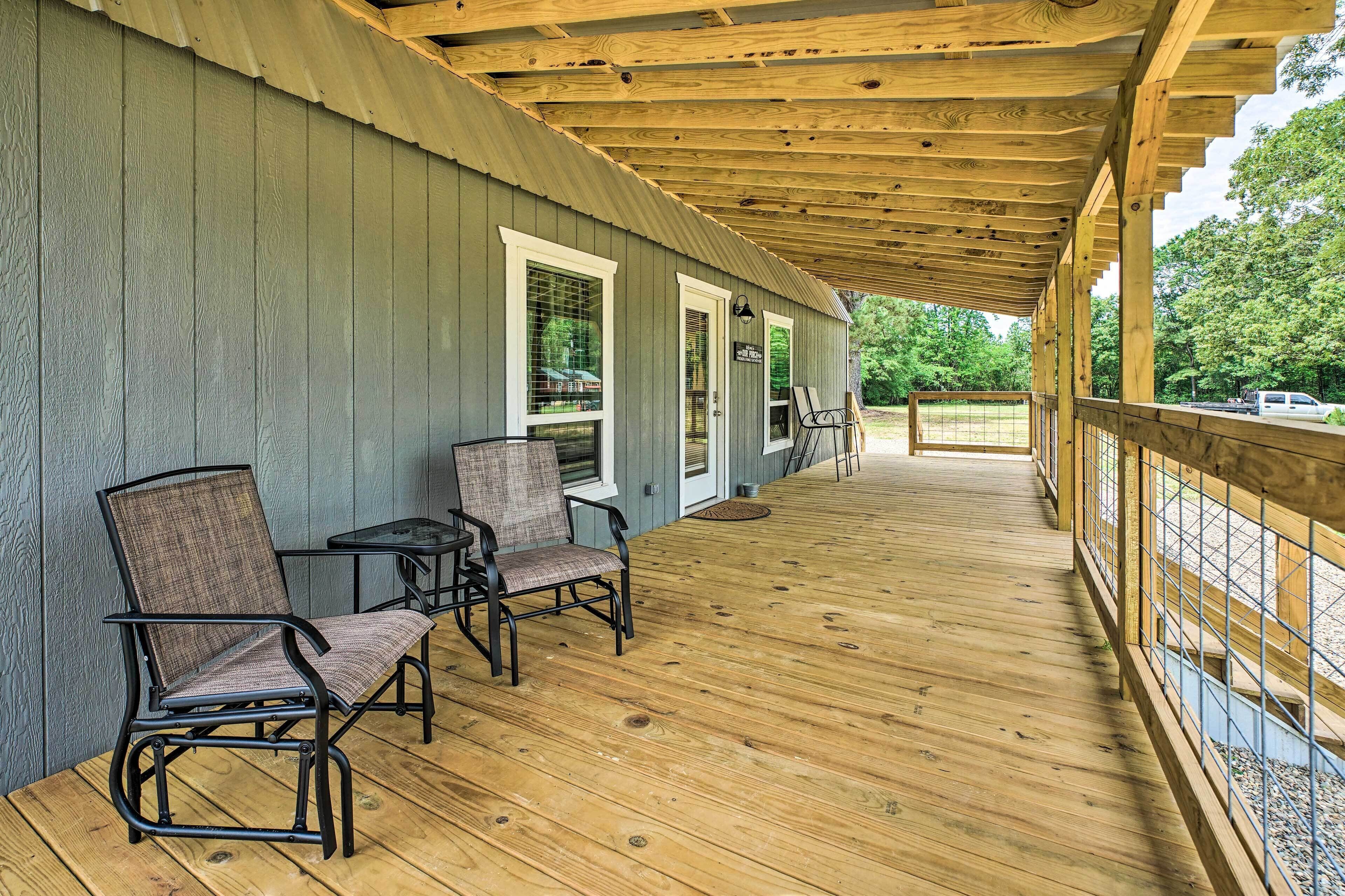 A covered porch with wooden flooring, two chairs, and a table.