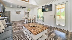 Amplia sala de estar con comedor, una mesa de centro y una cocina al fondo.