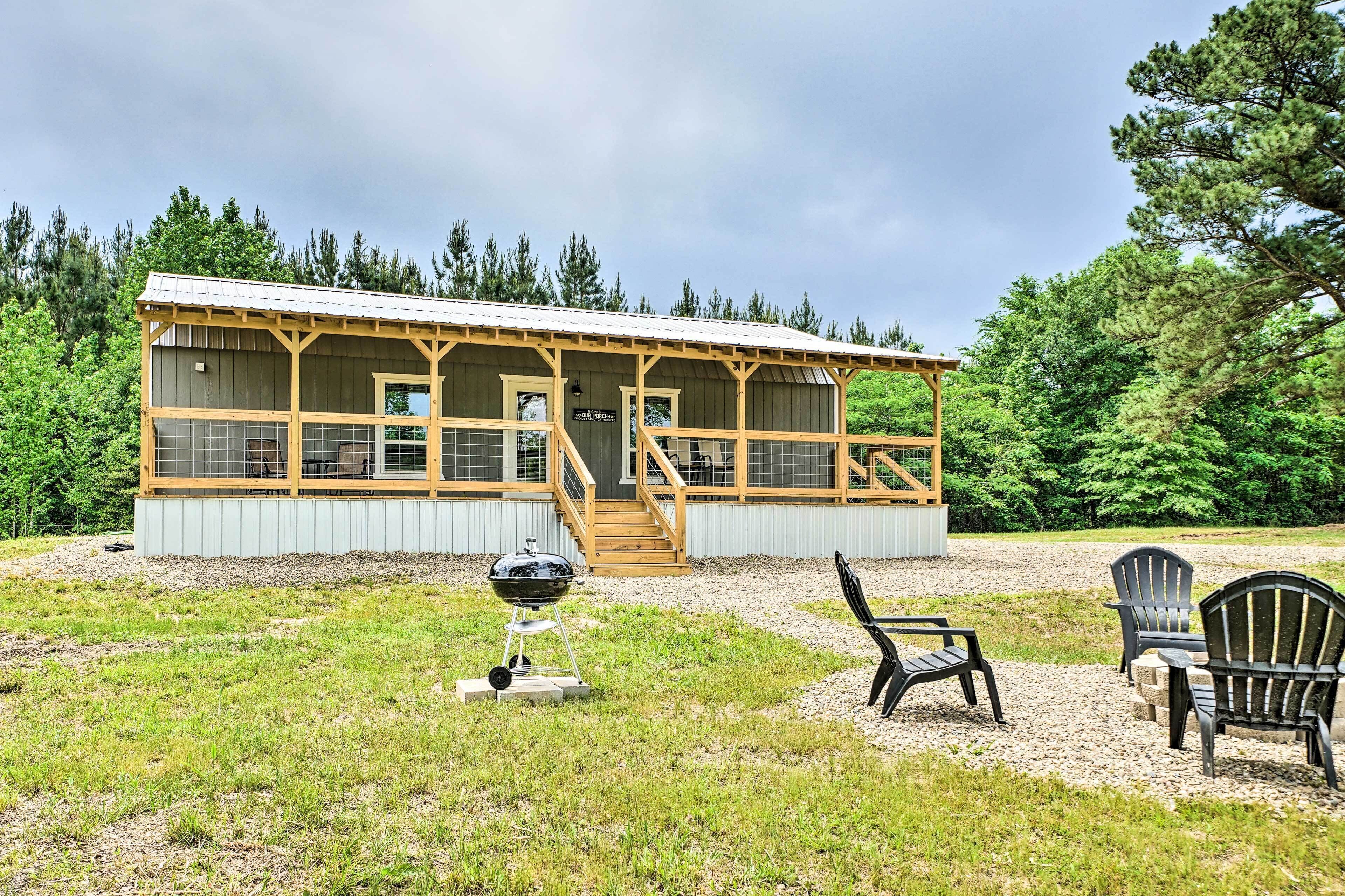 A cabin with a porch, a barbecue grill, and outdoor seating.