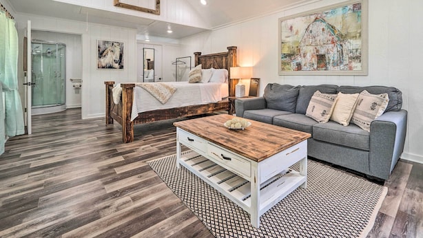 Un salón amplio con un sofá grande de color gris, una mesa de centro de madera y una cama con cabecero de madera.