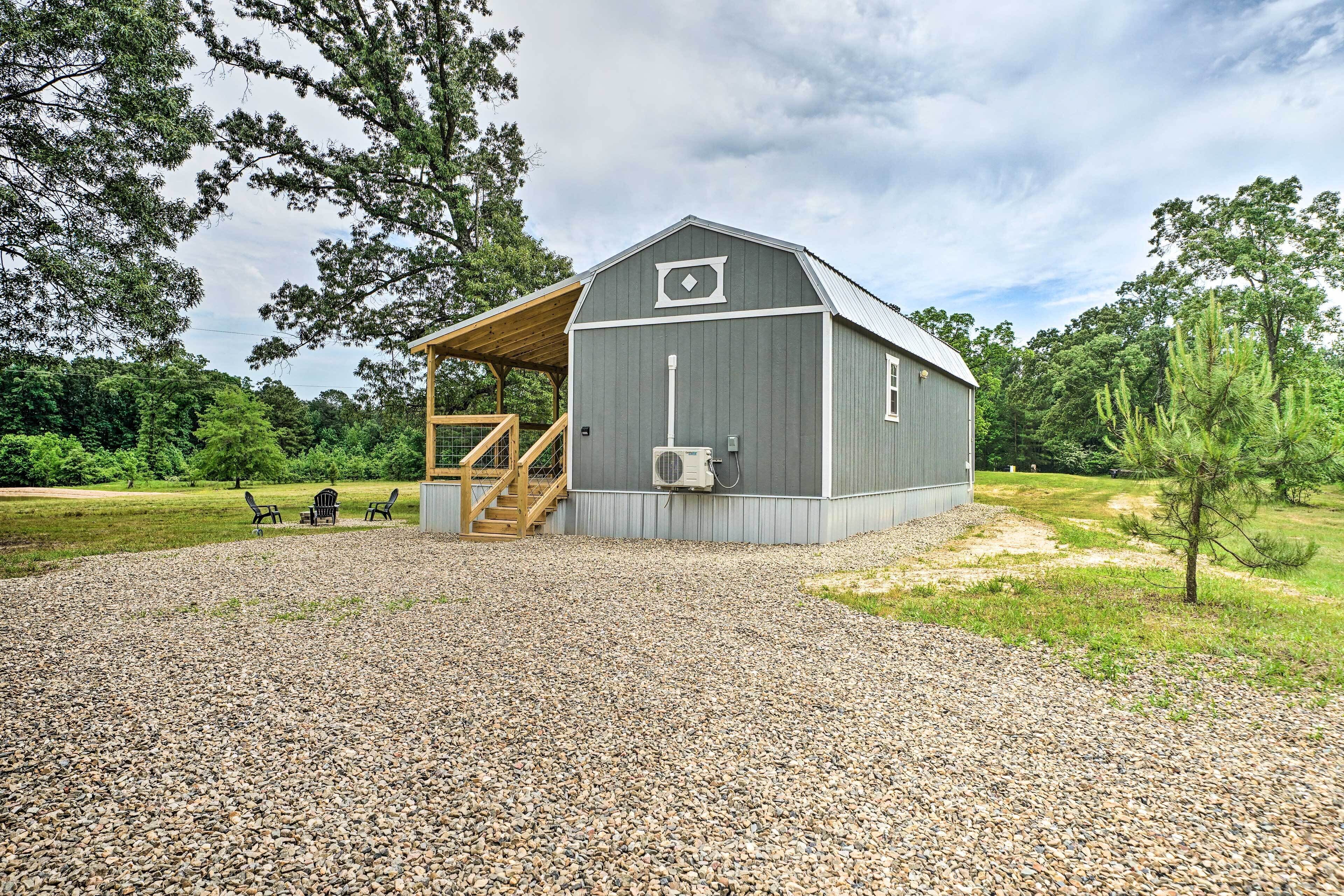 A rustic barn with a covered porch, gravel driveway, and outdoor seating area.