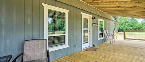 A covered porch with a wooden deck, two chairs, and a small table.