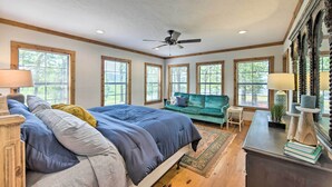 A bedroom with a large bed, a green sofa, a desk, and a ceiling fan. - The Bird Cabin Peaceful Refuge in East Texas (Edom)