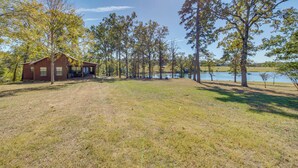 A rustic cabin with a porch, surrounded by trees and a lake. - The Bird Cabin Peaceful Refuge in East Texas (Edom)