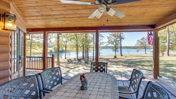 A covered outdoor seating area with a table and chairs, a ceiling fan, and a view of a lake. - The Bird Cabin Peaceful Refuge in East Texas (Edom)