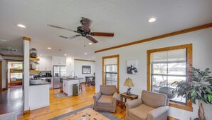 A spacious living area with a kitchen in the background, wooden flooring, and a ceiling fan. - The Bird Cabin Peaceful Refuge in East Texas (Edom)