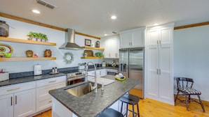 A modern kitchen with white cabinets, a stainless steel refrigerator, and a granite countertop. - The Bird Cabin Peaceful Refuge in East Texas (Edom)