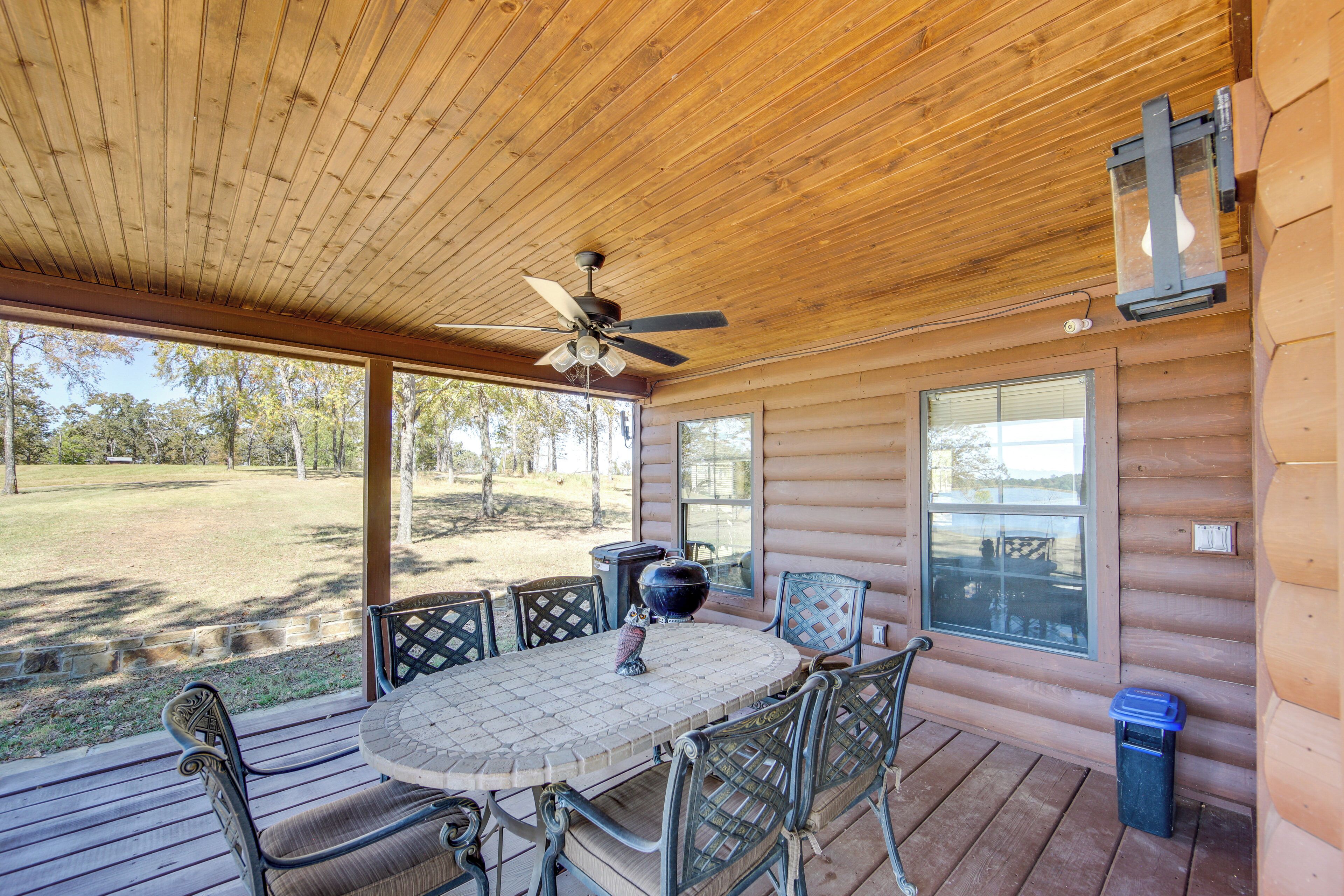 A wooden deck with a table and chairs, a ceiling fan, and a lantern.