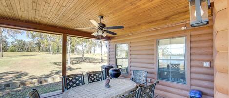 A wooden deck with a table and chairs, a ceiling fan, and a lantern.