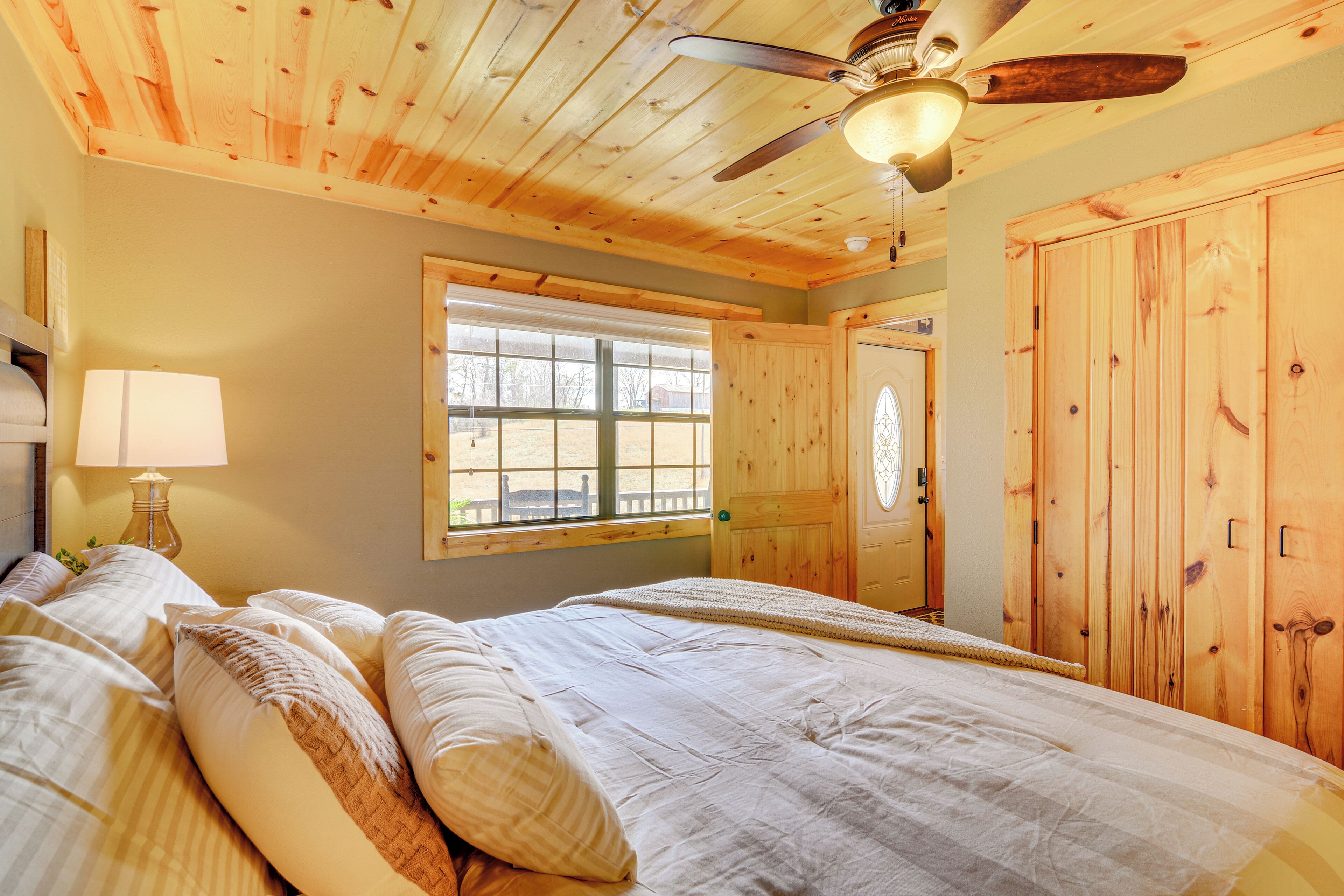 Une chambre avec un plafond en bois, un lit avec plusieurs oreillers, une fenêtre et une porte.