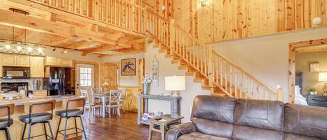 Un vaste espace de vie agrémenté d’un escalier en bois, d’un canapé en cuir et d’une cuisine située au fond de la pièce.