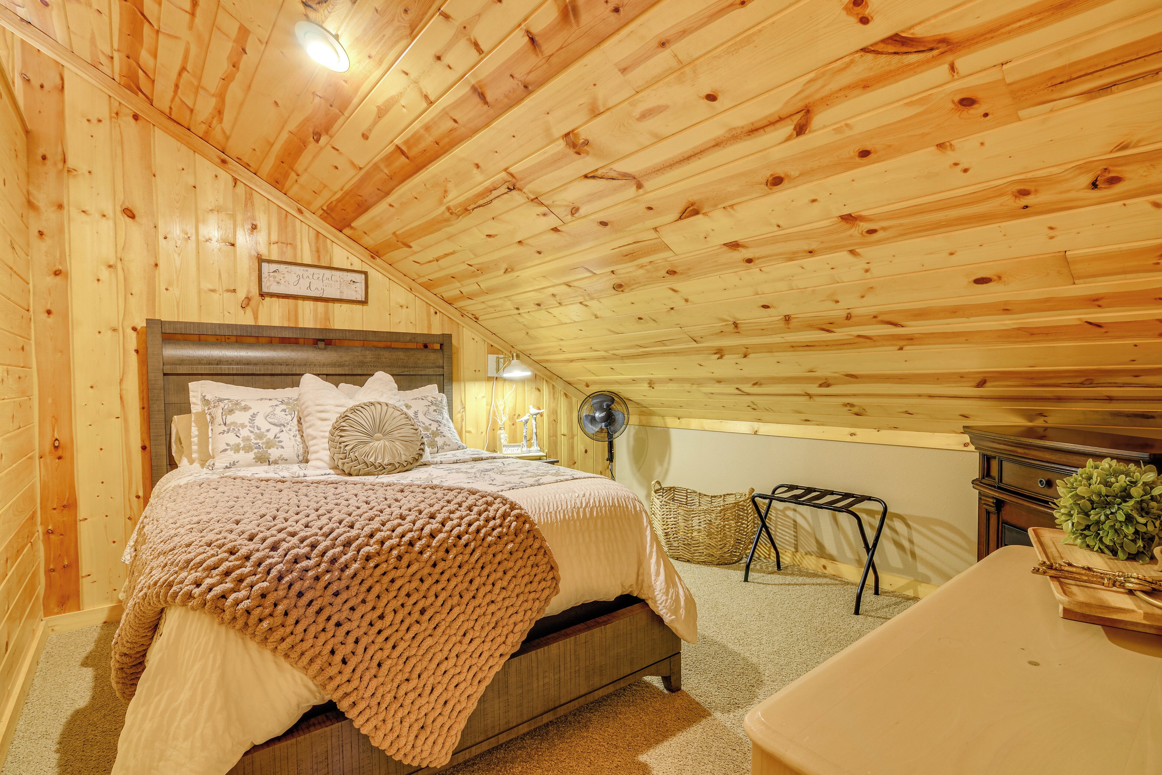 Ein gemütlicher Holzraum mit einem Bett, einem kleinen Tisch und einem Ventilator.