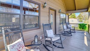 A covered porch with rocking chairs, a small table, and a lantern. - Modern Cabin w/ Grill Near Golf & Bass Fishing! (Burkesville)