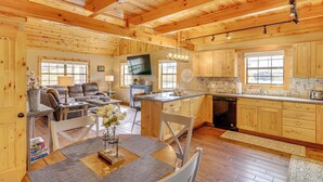 A spacious wooden cabin with a dining area, kitchen, and living room. - Modern Cabin w/ Grill Near Golf & Bass Fishing! (Burkesville)