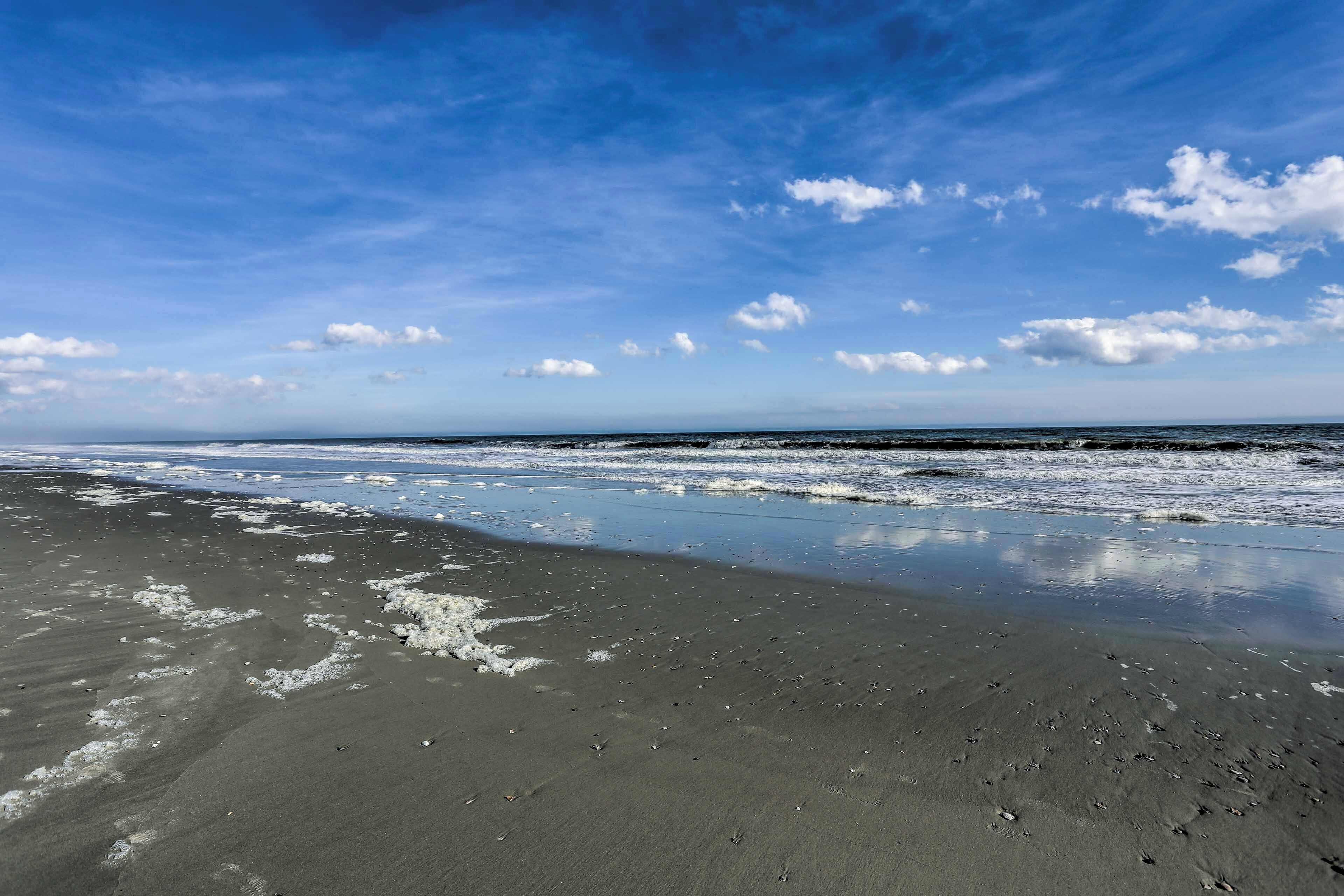 Une plage avec un ciel dégagé et des vagues calmes.