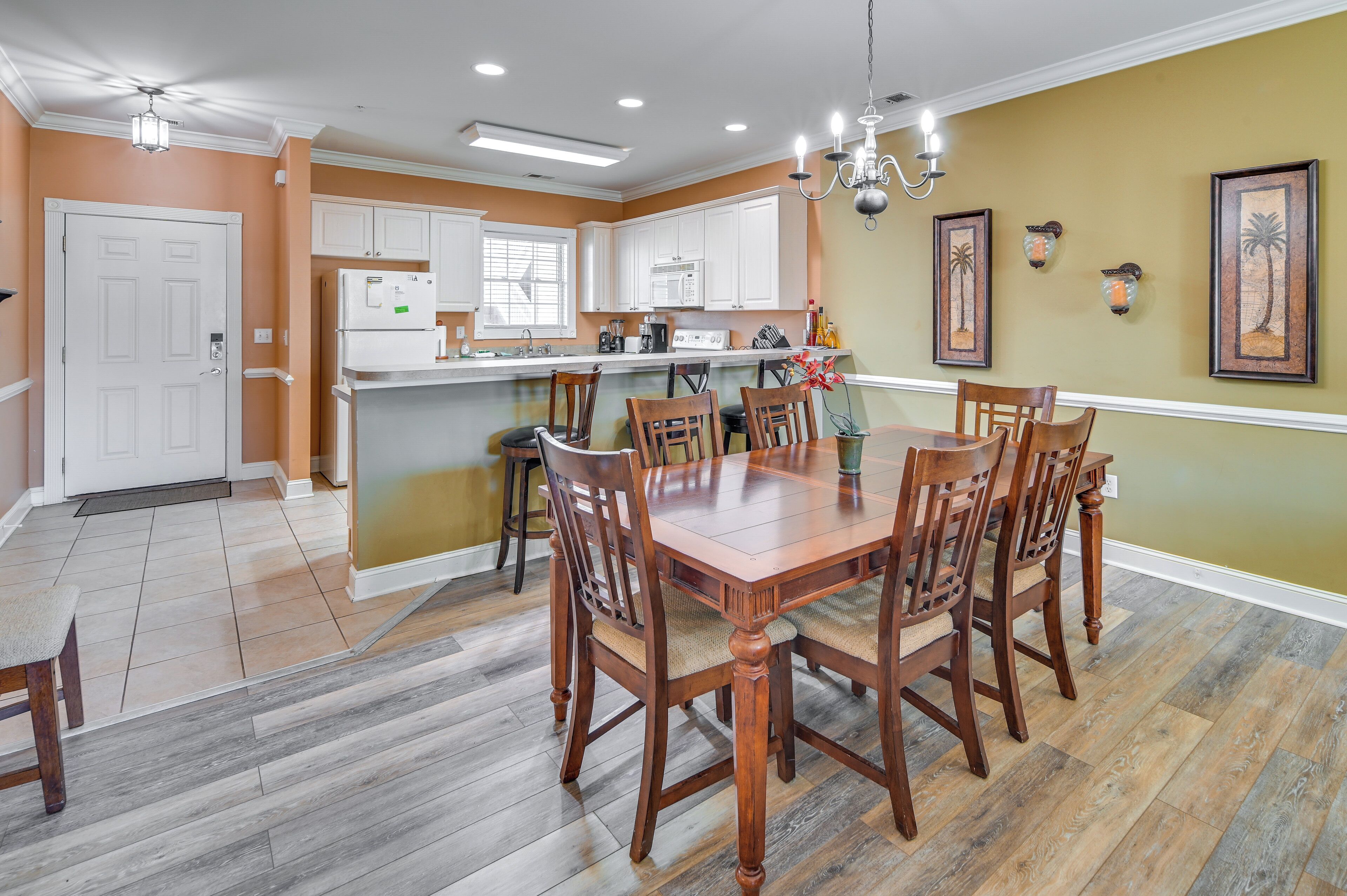 A kitchen with white cabinets, a wooden dining table, and chairs.