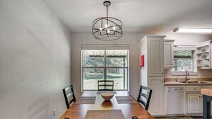 A dining area with a wooden table, four chairs, a central bowl, and a pendant light. - Granbury Cottage, Steps to Lake & Dock! (Granbury)