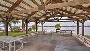 A covered picnic area with benches and picnic tables, overlooking a body of water. - Granbury Cottage, Steps to Lake & Dock! (Granbury)