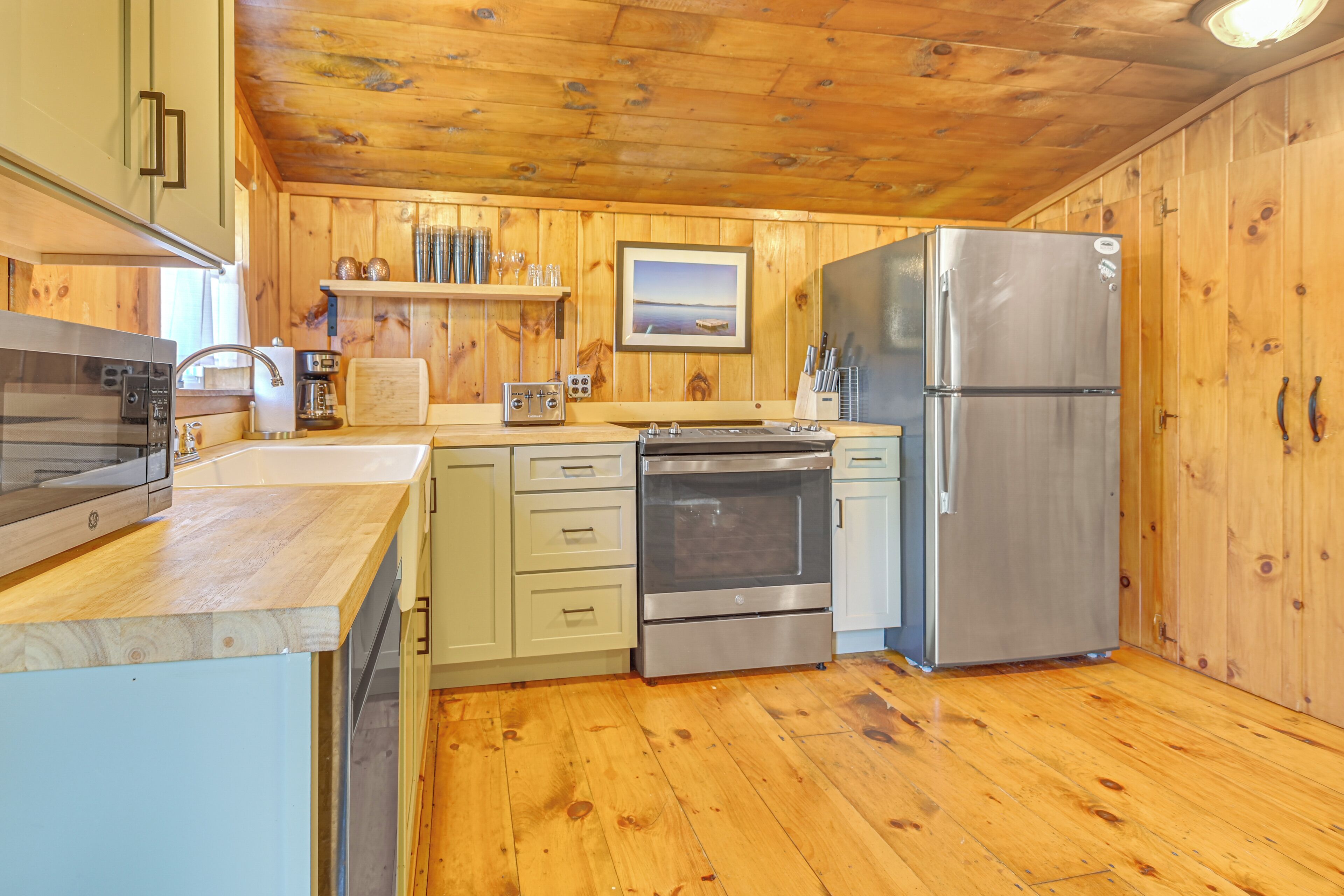 A compact kitchen with wooden walls, a stainless steel refrigerator, and a built-in oven.