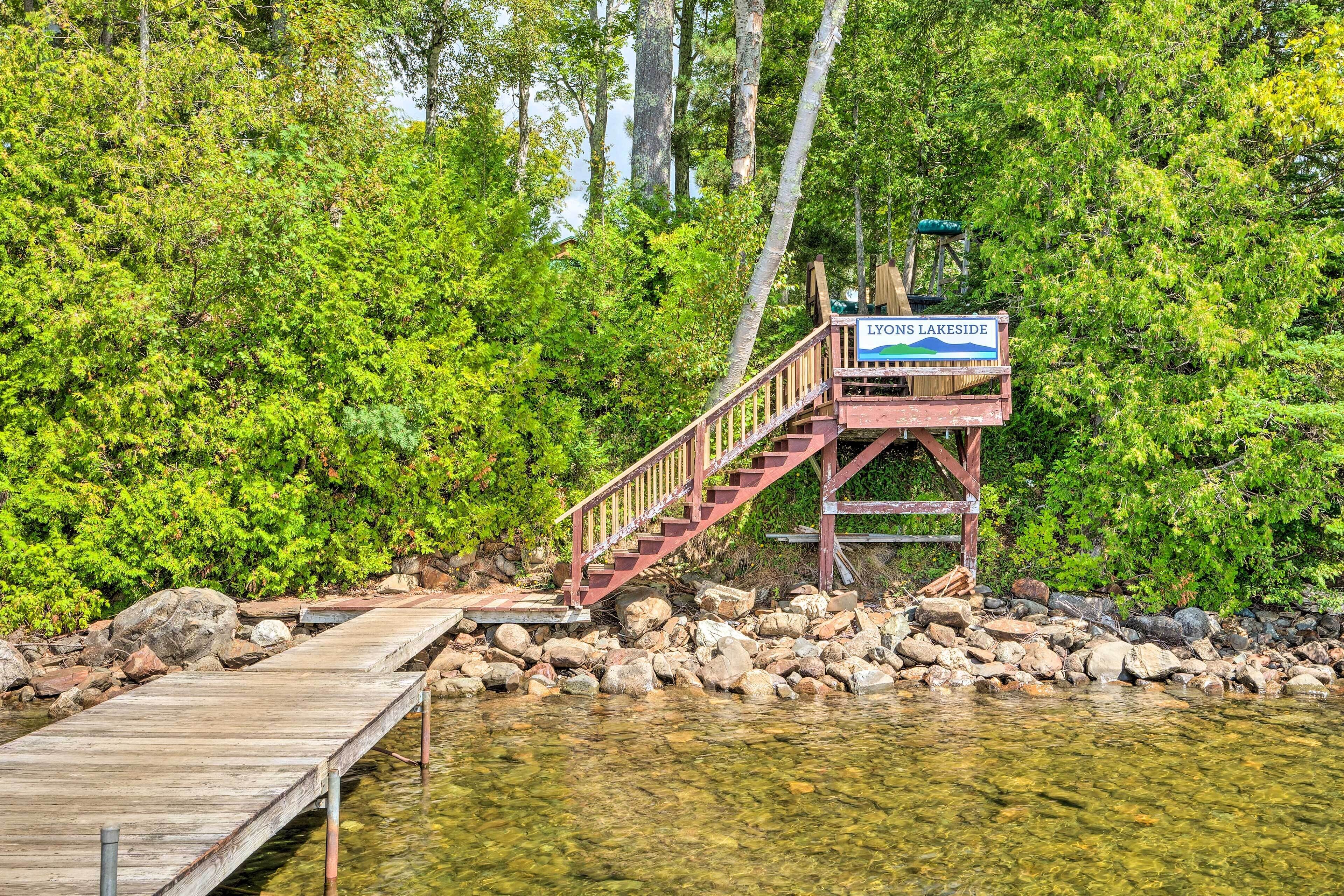 A wooden dock leading to a wooden platform with a sign reading "LYONS LAKESIDF".
