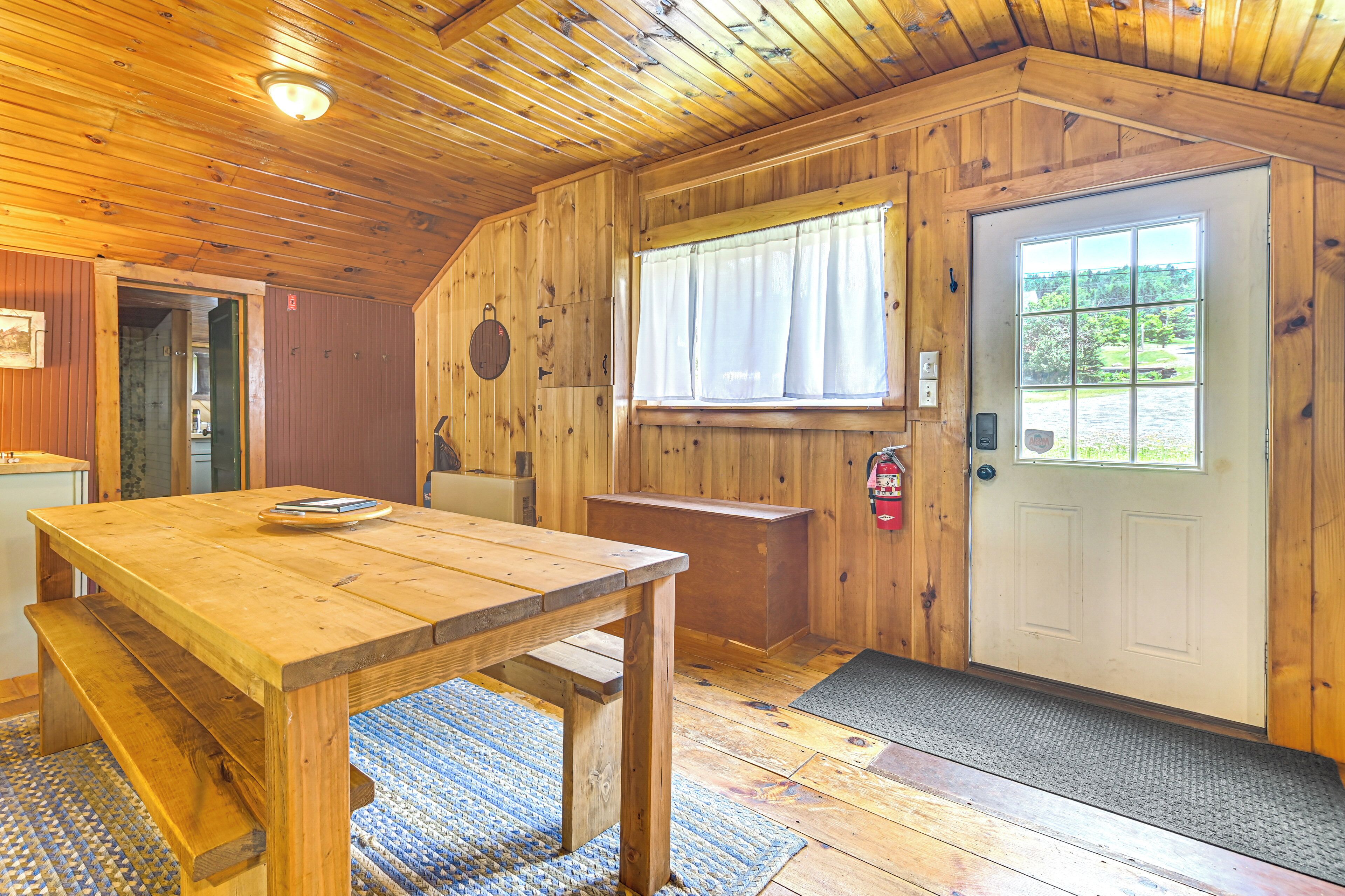 A wooden interior with a wooden table, bench, and a door with a window.