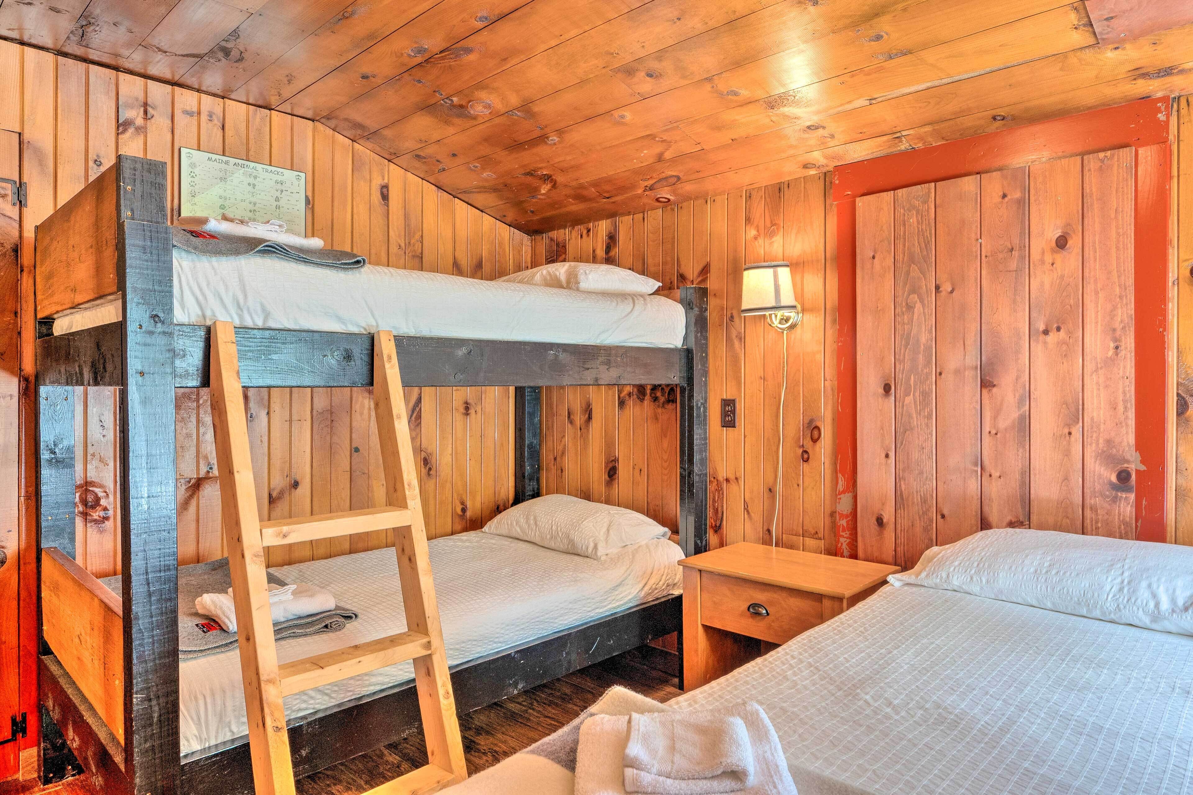 A wooden cabin room with bunk beds, a ladder, and a nightstand.