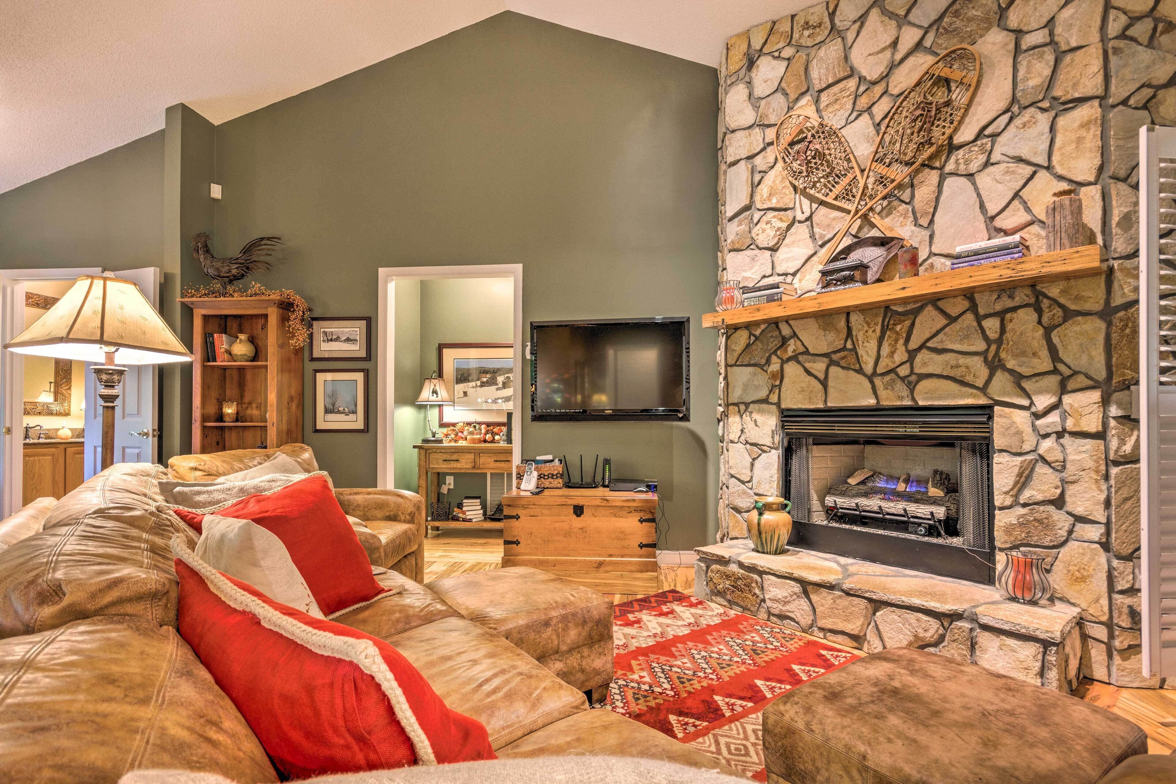 A cozy living room with a stone fireplace, leather sofa, and a television.