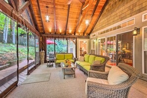 A covered patio with wicker furniture, a glass table, and a view of the backyard. - Screened Porch + 3 Decks: Beech Mountain Cabin (Banner Elk)