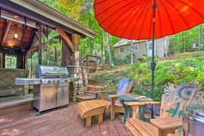An outdoor deck with a grill, wooden chairs, and a red umbrella. - Screened Porch + 3 Decks: Beech Mountain Cabin (Banner Elk)