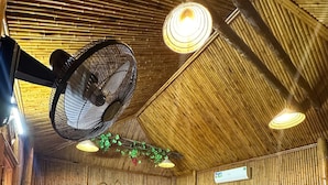 Una habitación con dos camas de madera, un pequeño armario de madera y un ventilador de techo.