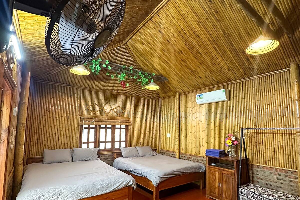 A room with two wooden beds, a small wooden cabinet, and a hanging fan.