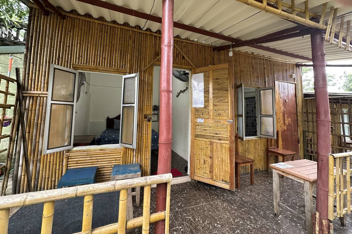 A traditional bamboo structure with a partially open door, a small table, and a bench.