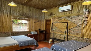 Una habitación con dos camas, un armario de madera, una mesita y un sillón colgante.
