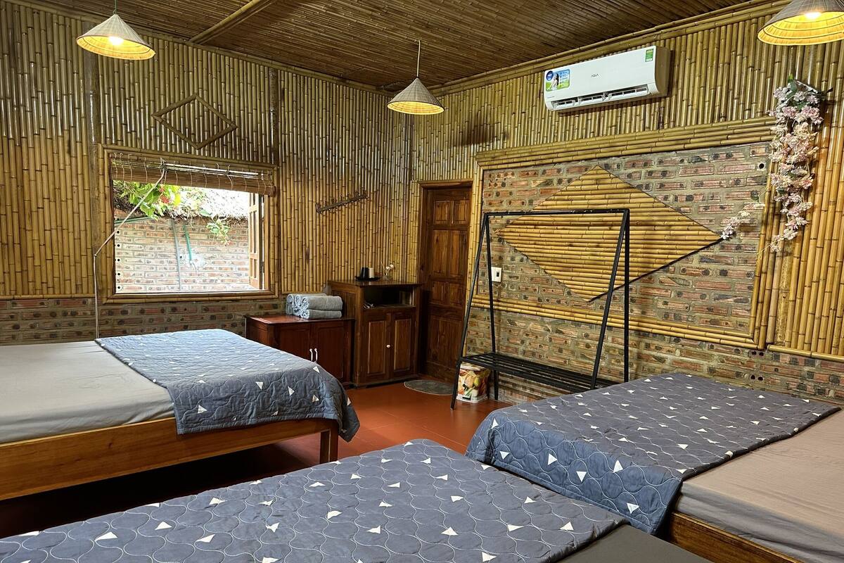A room with two beds, a wooden wardrobe, a small table, and a hanging chair.