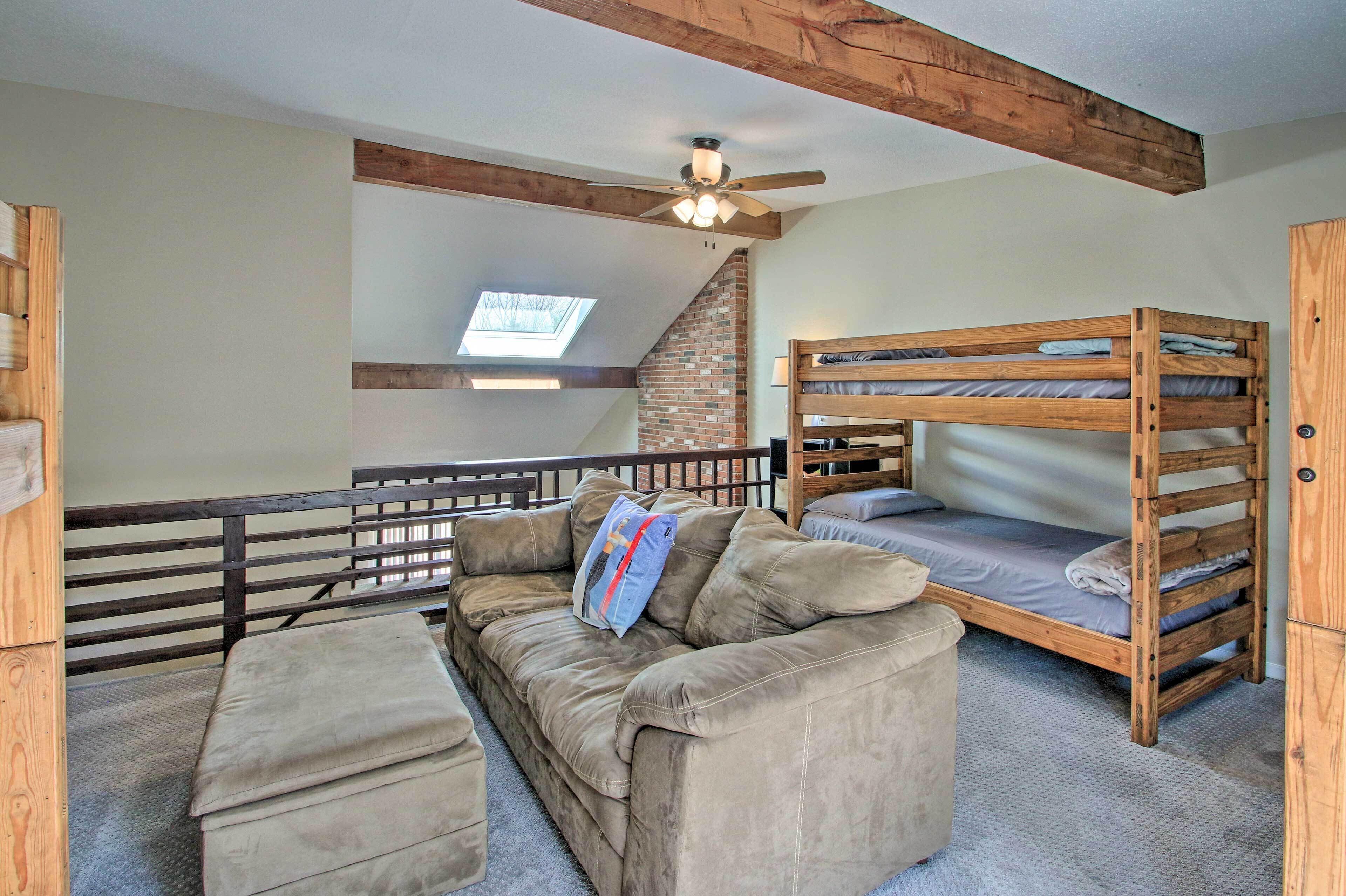 A room with a bunk bed, a sofa, and a ceiling fan.