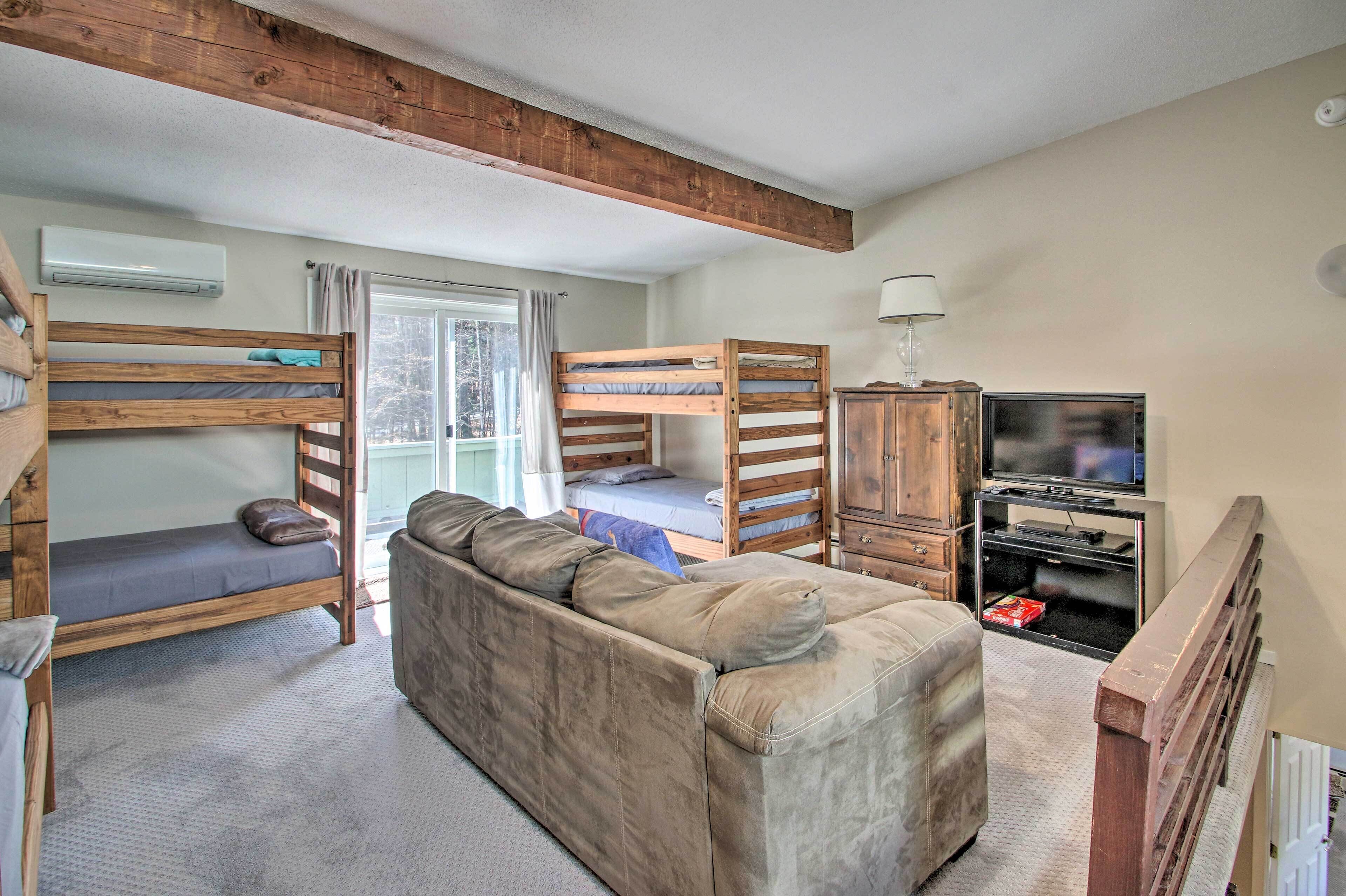 A compact room with bunk beds, a sofa, a TV, and a cabinet.