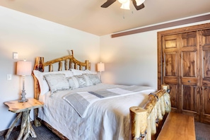 A bedroom with a wooden headboard, a bed with white bedding, a nightstand with a lamp, and a wooden bench.