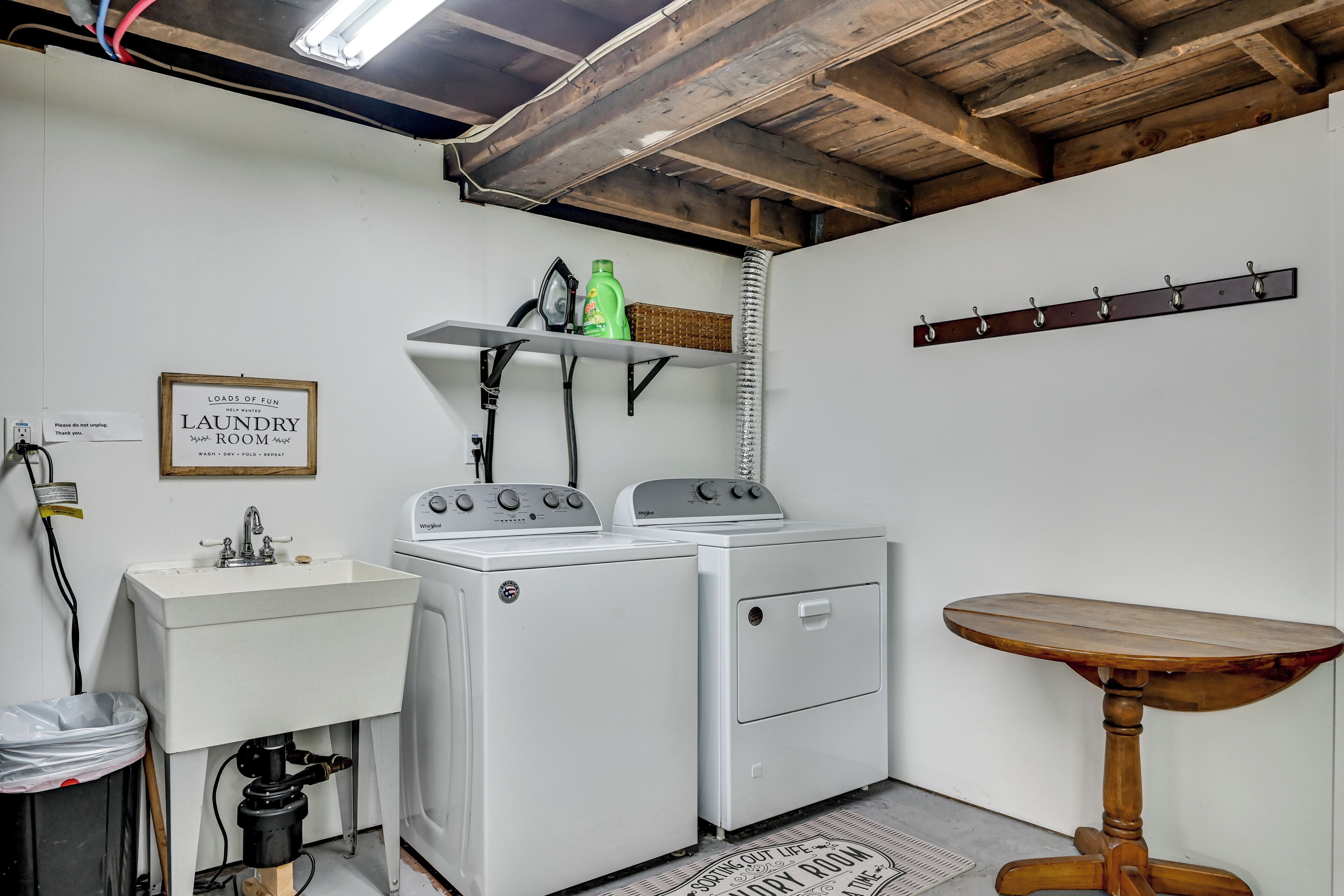 A laundry room with two washing machines, a sink, a table, and a sign that reads "LOADS OF FUN LAUNDRY ROOM."