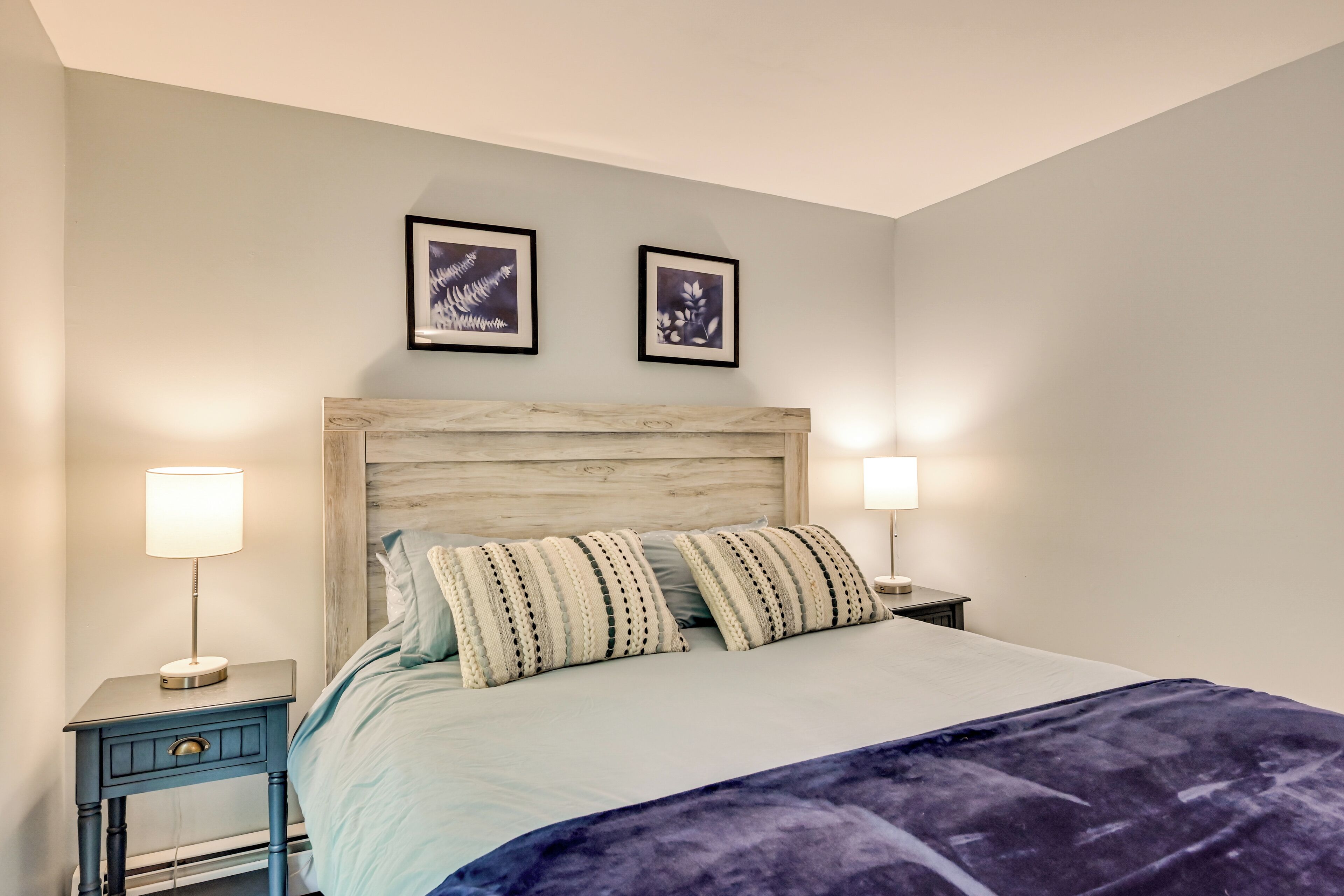 A neatly made bed with striped pillows, a wooden headboard, and two bedside lamps.